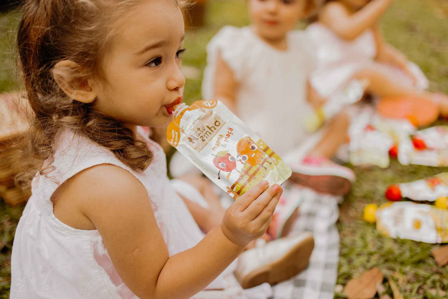 Papinha Organica Natural de Fruta sabor Manga e maça Natuzinho - criança sentada no parque comendo natuzinho papinha natural