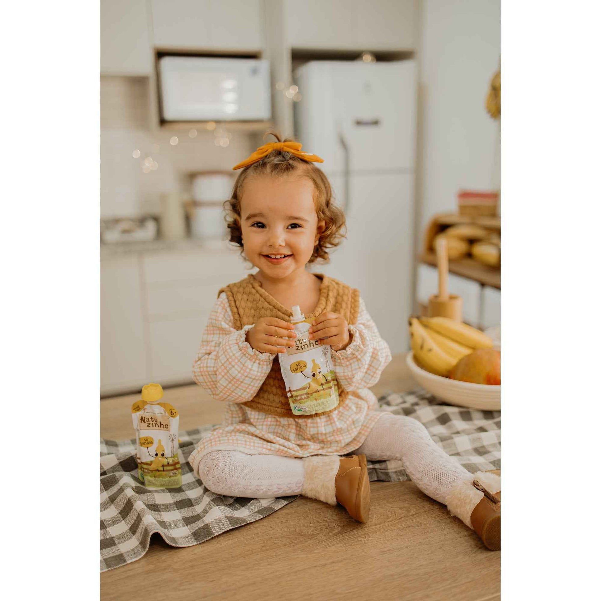 Kit Papinha Organica Natuzinho Banana Bebe 12 unidades - criança saboreando natuzinho em cima do balcao