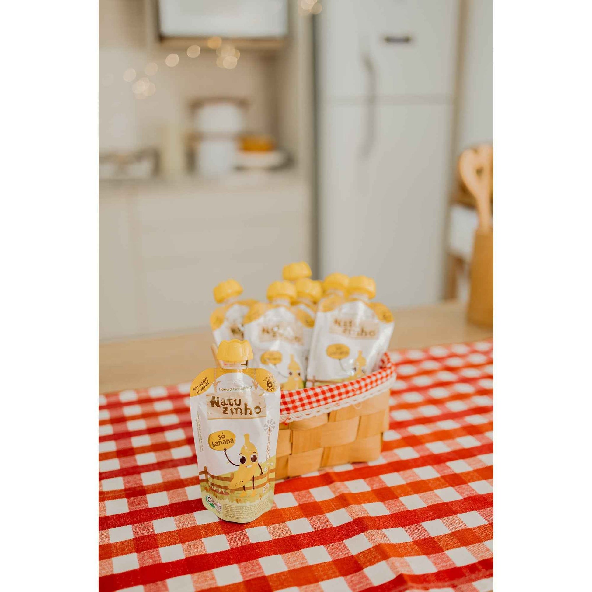 Kit Papinha Organica Natuzinho Banana Bebe 12 unidades - embalagem ao lado de pedaços de banana