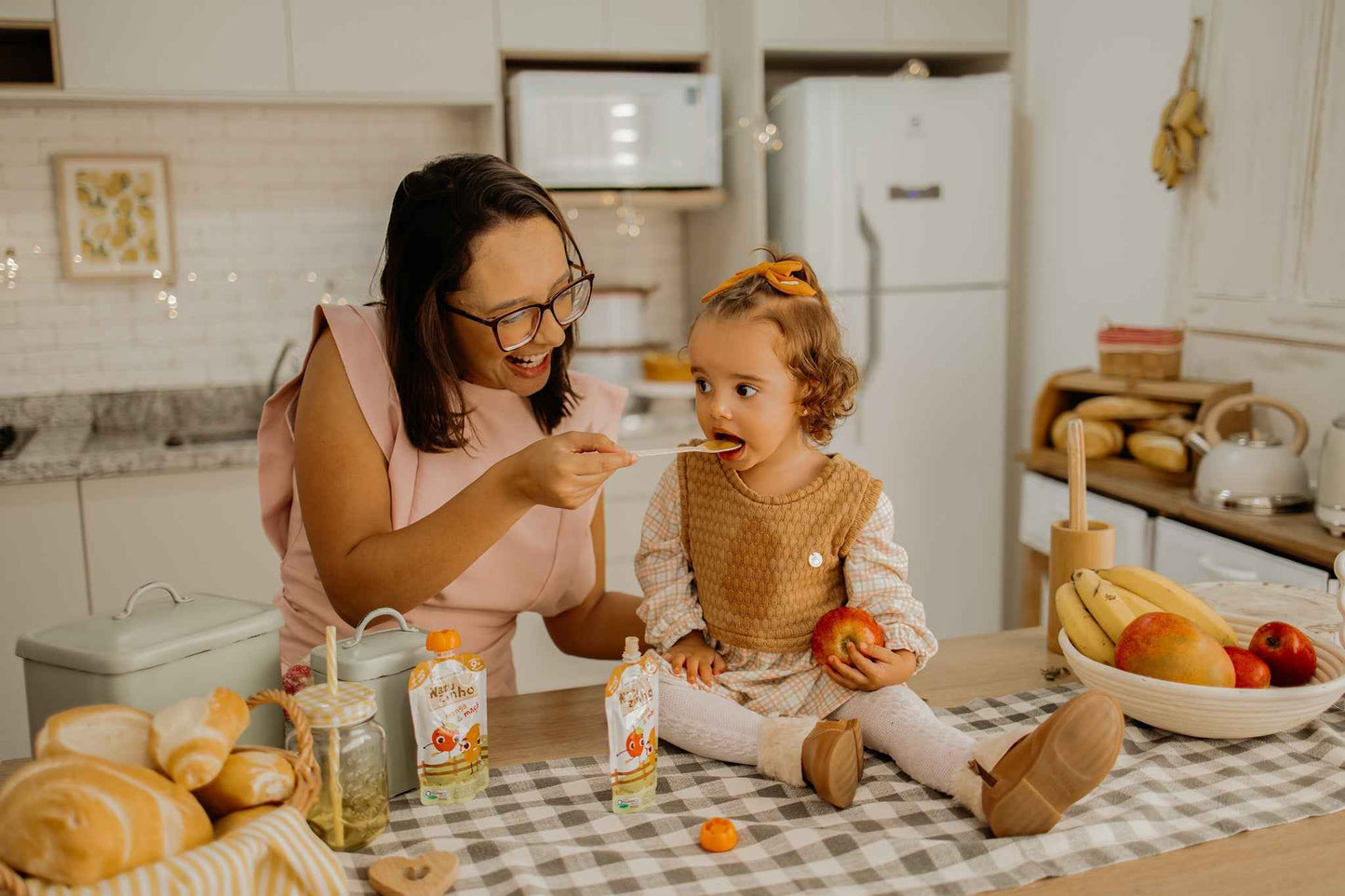 Papinha Organica Natural de Fruta sabor Manga e maça Natuzinho - mae sorrindo alimentando a filha com papinha organica natuzinho