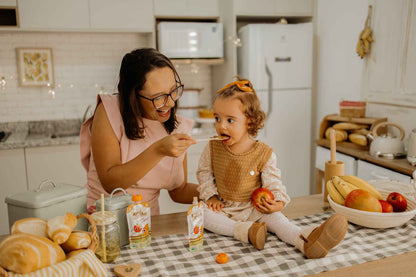 Papinha Organica Natural de Fruta sabor Manga e maça Natuzinho - mae sorrindo alimentando a filha com papinha organica natuzinho