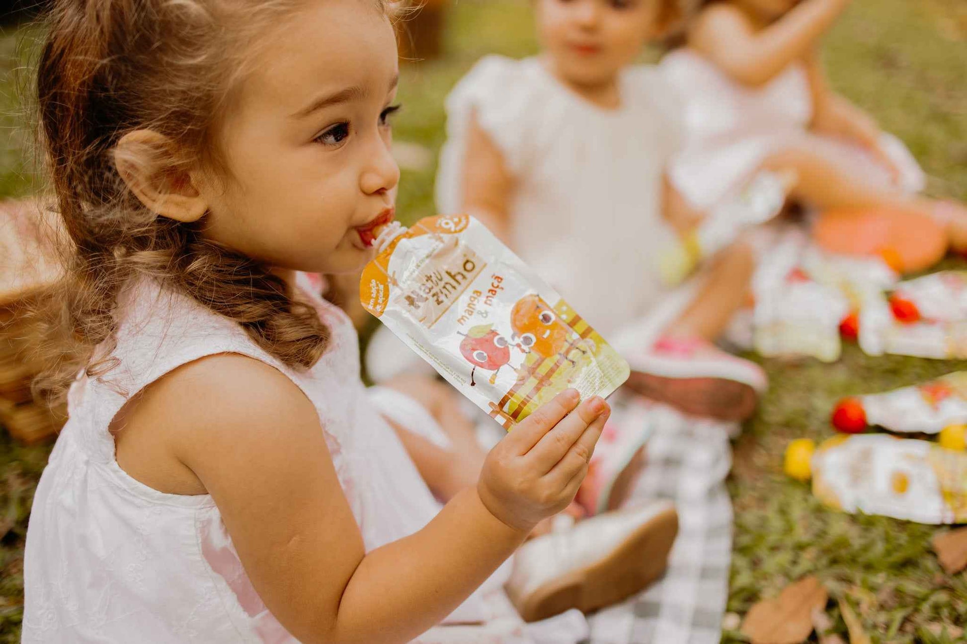 Papinha Organica Natural de Fruta sabor Manga e maça Natuzinho - criança sentada no parque comendo natuzinho papinha natural