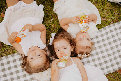 Papinha Organica Natural de Fruta sabor Manga e maça Natuzinho - 3 crianças deitadas no parque comendo papinha natural